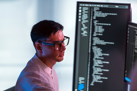 Focused developer and programmer works at modern office workstation, coding and debugging software...