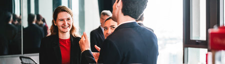 Business professionals network by coffee station in modern office. Workplace conversation shows colleagues meeting, teamwork, and collaboration during a friendly break with city views.の写真素材
