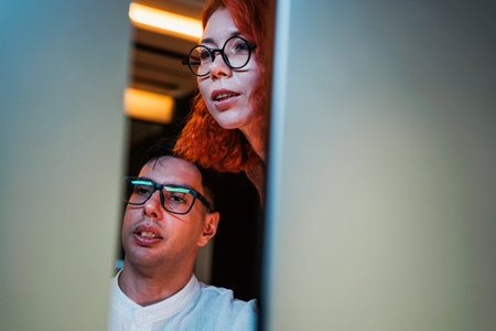 Two developers collaborating while looking at a computer screen. Teamwork in coding, problem-solving, and learning technology skills for business, innovation, and digital transformation projects.の写真素材