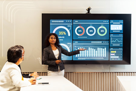 Professional presents analytics dashboard on large screen in modern meeting room, explaining data,...