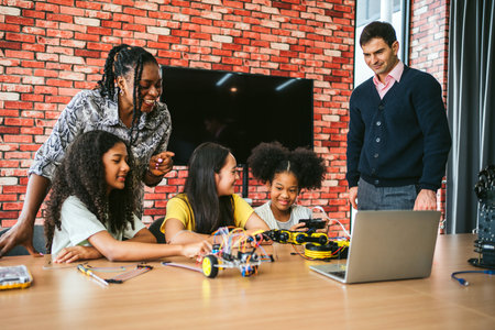 Diverse students and mentors brainstorm in classroom lab, coding and testing wheeled robot around...