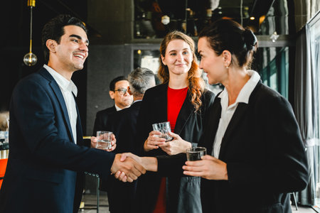 Business professionals greet each other with a handshake while networking at a corporate event, capturing a moment of connection, professionalism, and partnership in a formal setting.の写真素材