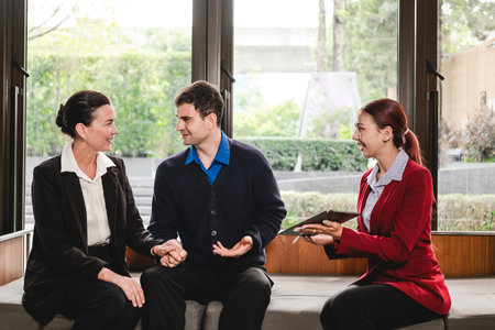 A professional advisor meets with a couple in a modern office lounge, discussing plans using a...