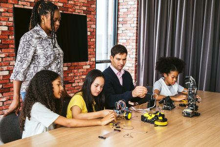Kids collaborate with two instructors to build and test small robots, wiring circuits and components during a classroom STEM workshop.