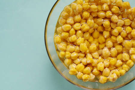 Organic chickpea soaked in water in a bowl on a blue background