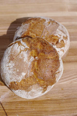 Freshly baked bread on wooden cutting board isolated on grass background, top viewの写真素材