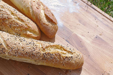 French baguette on the wooden cutting board. Green grass on the background  Close-up. Selective focus.の写真素材