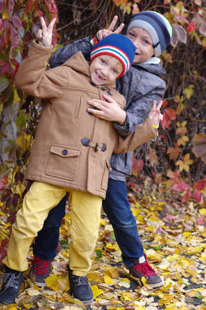 Funny and happy children are played against the background of autumn yellow leavesの写真素材