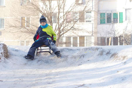 Cute Child sledding. Toddler boy riding a sledge in the snow