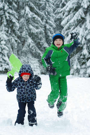 Happy boys playing on a winter walk in nature. Children jumping and having fun in winter parkの写真素材