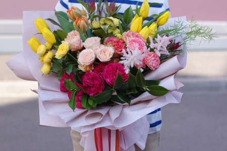Little smiling boy standing with a flower bouquet. Beautiful flowers for motherの写真素材