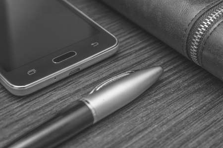 Men's accessories with a wallet, pen, smartphone on the background of the table black and white...