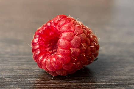 One red raspberry on a wooden background. Berries concept, side viewの写真素材