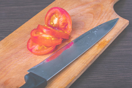 chopped tomatoes into pieces and a sharp knife on a cutting boardの写真素材