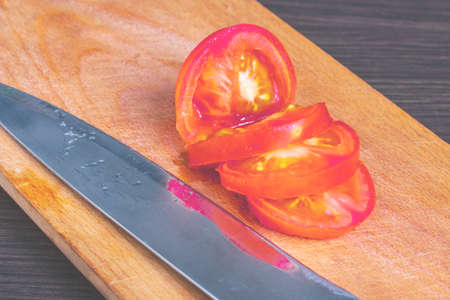 chopped tomatoes into pieces and a sharp knife on a cutting boardの写真素材