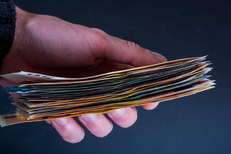 Human hand holding money - fifty-twenty-ten euro banknotes isolated on a dark gray backgroundの写真素材