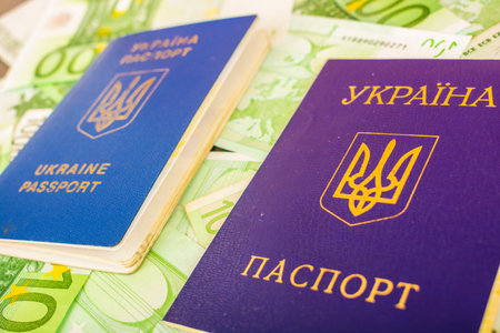 Two Ukrainian passports one is wounded by the second civil passport against the background of the euro banknotes in the face value of 100の写真素材
