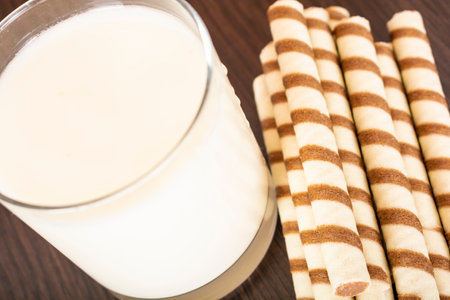 a glass of yogurt with a wafer tubule on a black background and a brick wall, free space for text, natural lightの写真素材