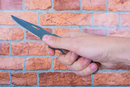 folding knife in male hands, against a background of brick orange wallの写真素材
