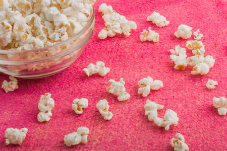 popcorn in a glass plate, on a pink uneven backgroundの写真素材