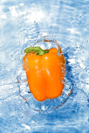 Yellow pepper dropped into water with bubbles isolated on whiteの写真素材