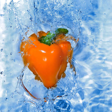 Yellow pepper dropped into water with bubblesの写真素材