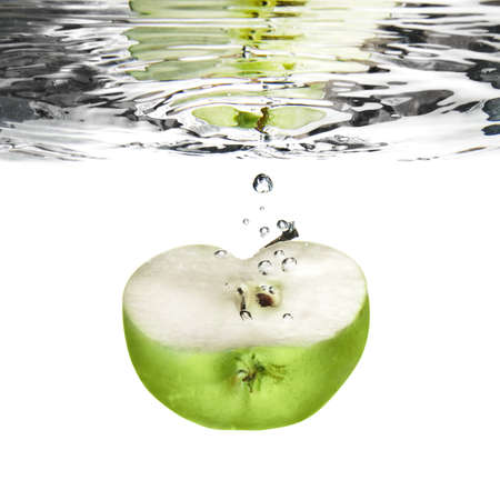 green apple dropped into water with bubbles isolated on whiteの写真素材
