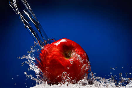 Green apple with water splash on blue backgroundの写真素材