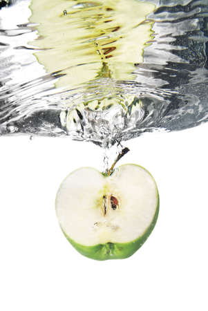 green apple dropped into water with bubbles isolated on white の写真素材