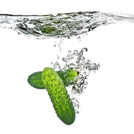 green cucumbers dropped into water isolated on white の写真素材