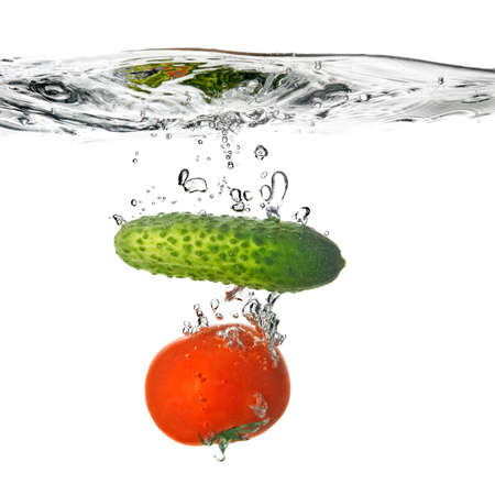 tomato and cucumber dropped into water isolated on whiteの写真素材