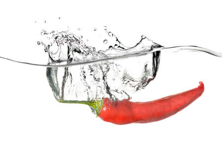 red pepper dropped into water with splash isolated on whiteの写真素材