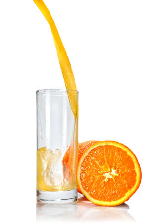 orange juice poring into glass isolated on whiteの写真素材