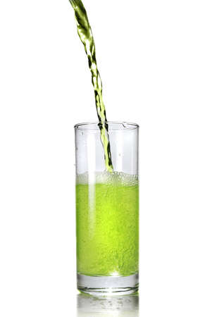 green juice pouring into glass isolated on whiteの写真素材