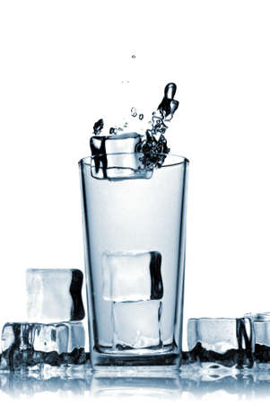 ice cubes dropped into glass with bubbles isolated on whiteの写真素材