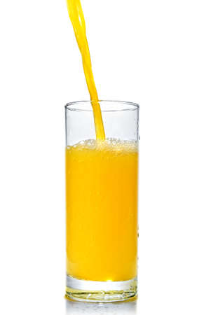 orange juice poring into glass isolated on whiteの写真素材