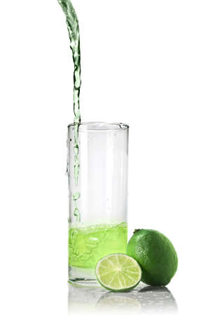 green juice with lime pouring into glass isolated on whiteの写真素材