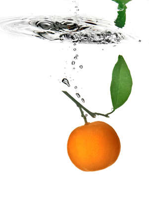tangerine dropped into water with bubbles on whiteの写真素材