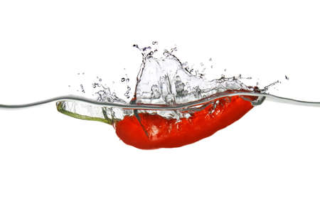red pepper dropped into water with splash isolated on whiteの写真素材