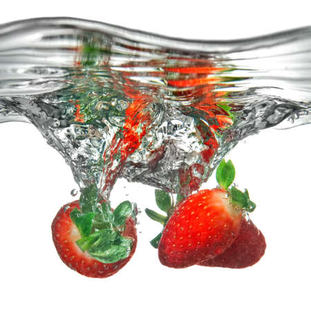 Fresh strawberry dropped into water with splash isolated on whiteの写真素材