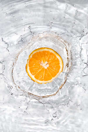 Fresh orange dropped into water with bubbles isolated on white