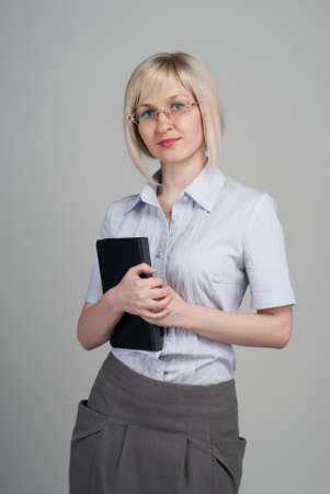 Young attractive businesswoman holding diary isolated on greyの写真素材