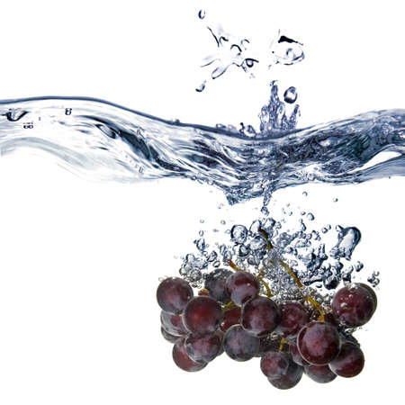 blue grape dropped into water with splash isolated on whiteの写真素材