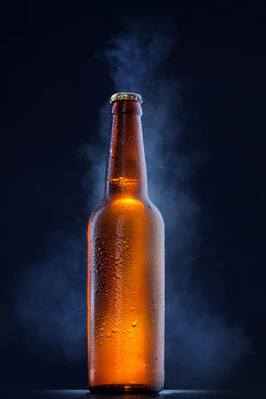 Cold beer bottle with drops, frost and vapour on blackの写真素材