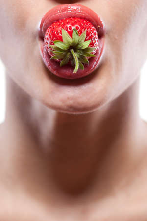 Young woman biting strawberry isolated on whiteの写真素材