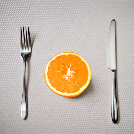 Healthy breakfast - fresh orange with knife and forkの写真素材