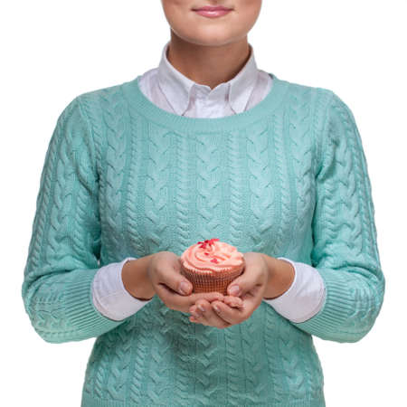 Young woman holding a pink cupcake decorated with hearts, isolated on white backgroundの写真素材