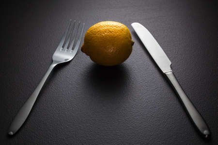 lemon with knife and fork on blackの写真素材