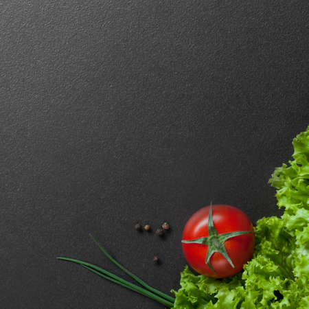 red tomato with green salad on black. top viewの写真素材