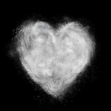 heart made of white powder explosion isolated on black backgroundの写真素材
